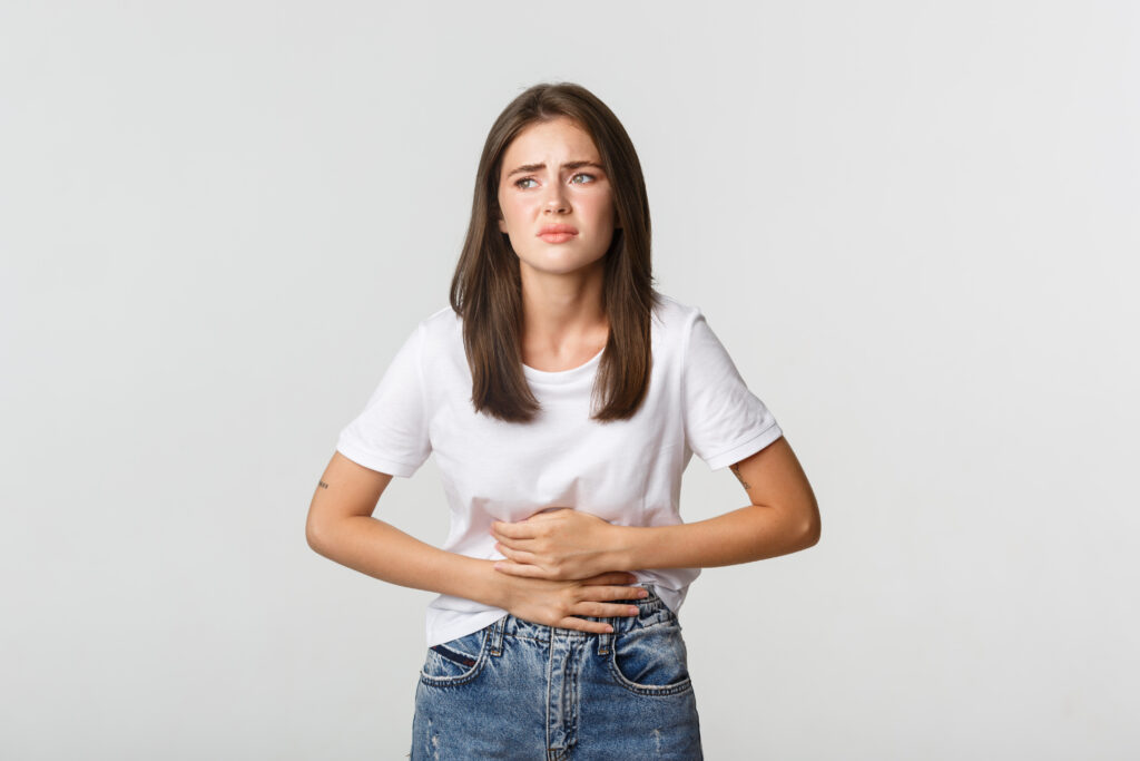 Woman having stomach ache, bending and holding hands on belly, discomfort from menstrual cramps